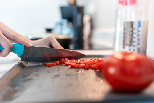 Person chopping fresh red tomatoes on cutting board