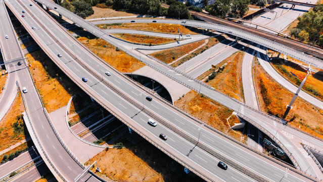 Traffic flows on multiple highways in an urban area during daytime. Cars move along the roadways of a busy highway system in a city setting.