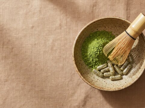 Green matcha green tea powder with bamboo whisk and herbal capsules on linen background