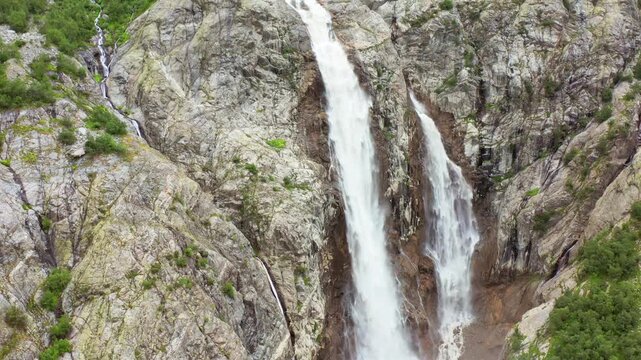 Shdugra Waterfall cascades in hovering aerial view down a steep rocky face below Mount Ushba near Mazeri, Svaneti, supporting geology research, hiking tourism, hydrology education and nature media.