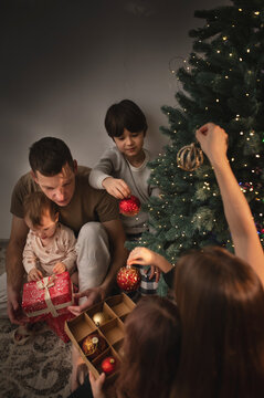 A large family of three children, mom and dad, are celebrating New Year's decorated christmas tree. A quiet, cozy family evening.