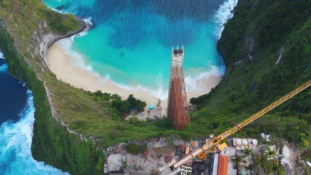 Glass elevator construction subject to legal compliance destruction order overlooking the iconic T-Rex cliff at Kelingking Beach, Nusa Penida, Indonesia, top-down view