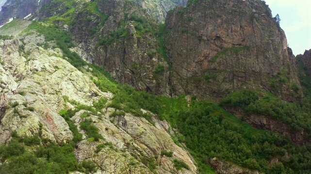 Alpine cliffs extend in circling aerial view across rugged Shdugra terrain near Mazeri, Svaneti, supporting geological survey, geotourism, habitat mapping and Caucasus mountain travel media.