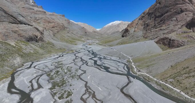 Tibet, China drone glide of a braided river valley along the sacred Mount Kailash kora trekking route on a bright sunny day.