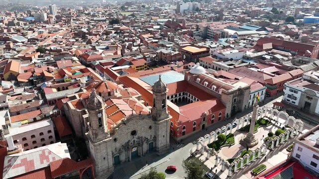 Aerial approach over the red-tiled roofs of Potosi, Bolivia, highlighting a magnificent colonial church in the historic downtown.
