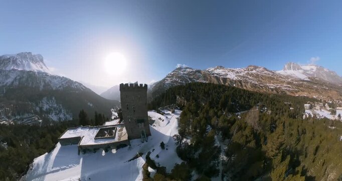 Belvedere Tower and castle ruins on snow ridge, mountains in Maloja Pass, Switzerland. Aerial drone wide angle orbiting, copy space