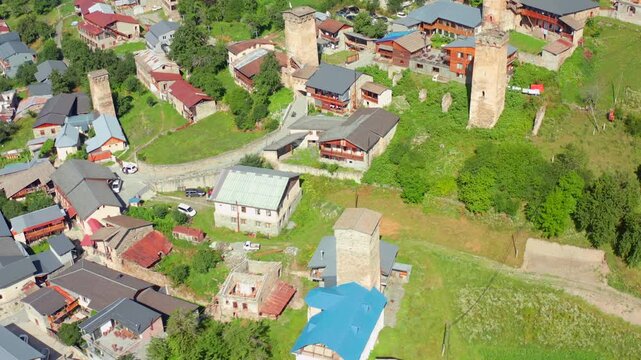 Mestia tower district fills circling aerial view above clustered homes and medieval stone defenses, supporting settlement mapping, cultural preservation, architecture research, Upper Svaneti tourism
