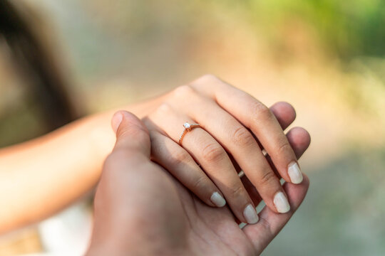 Loving couple holding hands with engagement ring