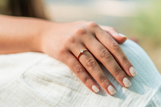 Woman's hand wearing engagement ring with diamond