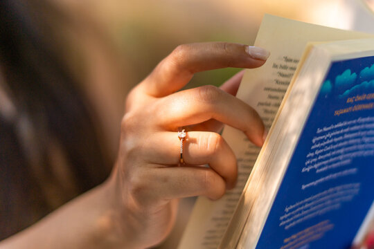 Woman's hand holding a book while reading outdoors