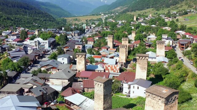 Svan tower houses fill forward aerial view across central Mestia neighborhoods, supporting medieval heritage, residential history, architectural research, cultural tourism, Georgian destination media