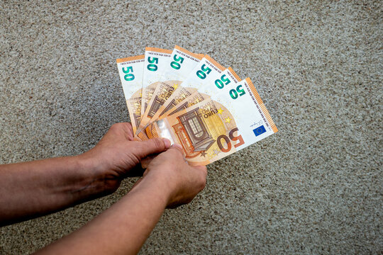 Hands Holding Five 50 EURO Banknotes Against Textured Concrete Background