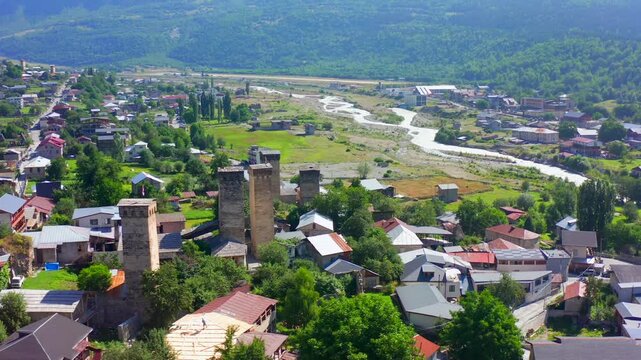 Mestia towers fill elevated aerial view as the drone circles above historic homes and the Enguri valley in Upper Svaneti, Georgia, supporting heritage tourism, medieval architecture, travel promotion