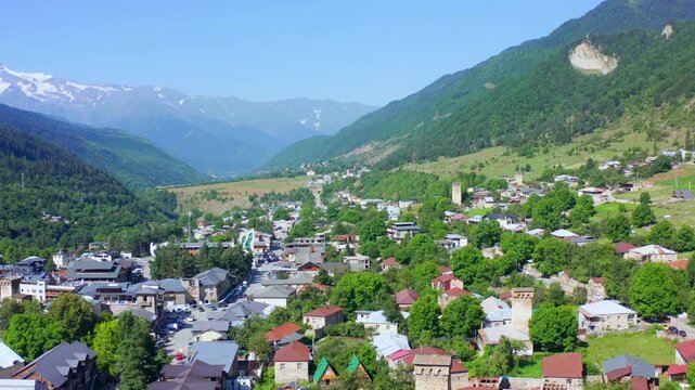 Mestia recedes in backward aerial view beneath Caucasus mountains and historic Svan towers, supporting destination marketing, heritage tourism, settlement geography and Upper Svaneti travel media.