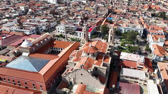 Cinematic drone footage of a historic Spanish colonial church and convent surrounded by the dense cityscape of Potosi, Bolivia.