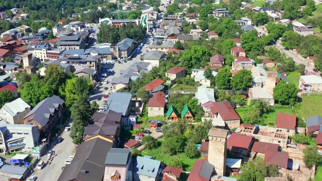 Central Mestia unfolds in forward aerial view above streets, homes and historic Svan towers, supporting urban tourism, settlement mapping, cultural geography and Georgian destination media use.