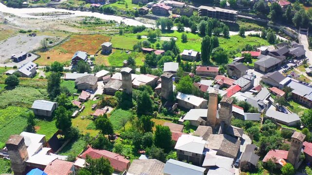 Mestia tower district rises in aerial view above historic Svan homes, gardens and the Enguri valley, supporting heritage tourism, settlement research, medieval architecture and Georgian travel media.