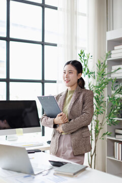Professional asian business woman holding clipboard in office