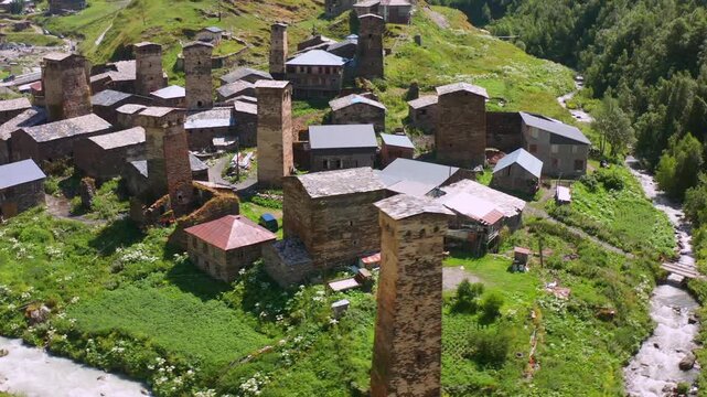 Svan towers circle in sideways aerial view above Chazhashi stone homes and the Enguri valley, supporting heritage conservation, medieval architecture, settlement research and Georgian cultural tourism