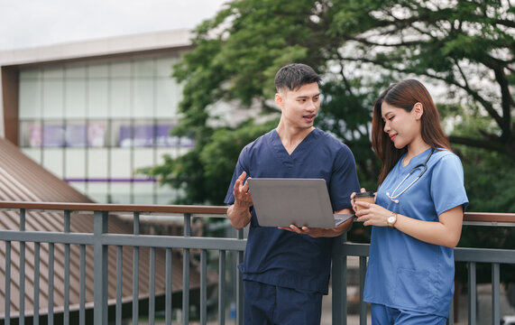 Asian medical team discussing work on laptop during coffee break