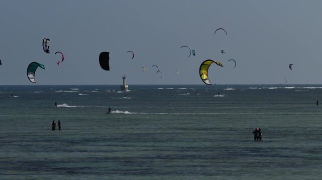 Aerial drone view of kite surfers riding the waves at My Hoa Beach in Vinh Hai, Khanh Hoa, Vietnam, showcasing a spectacular coastal landscape under bright sunlight.
