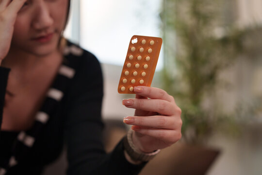 Asian woman holding pill blister pack with headache for illness and healthcare