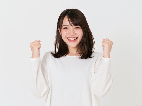 白いVネックのトップスを着てハツラツとしたガッツポーズを決める女性