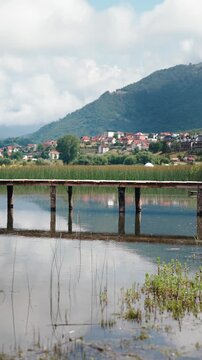 Static vertical view of a wooden pier on Plavsko Jezero, Montenegro, surrounded by scenic mountains and peaceful natural landscape.