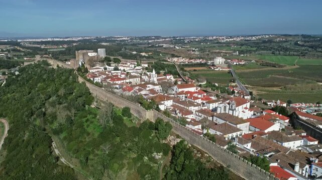 Aerial view of the historic walled town and castle of Obidos with terracotta rooftops and stone fortifications in Obidos, Leiria District, Portugal.