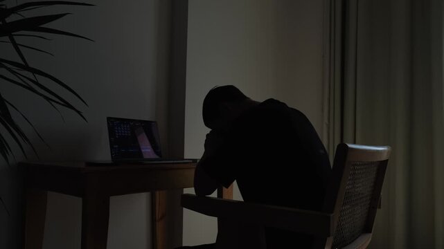A man sitting alone at home feeling overwhelmed by career uncertainty and job insecurity during a difficult period of professional and financial instability