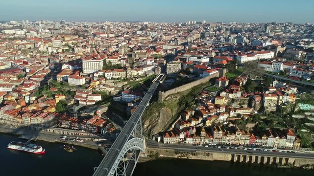 Aerial view of the historic Dom Luis I Bridge spanning the Douro River with the dense urban landscape of rooftops and buildings in Porto, Porto District, Portugal.