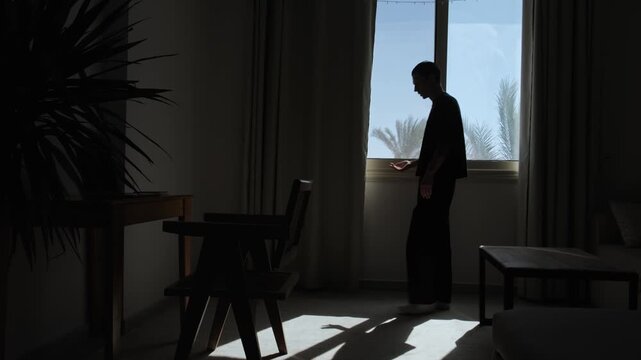 Silhouette of frustrated man walking alone and talking to himself in dark room, emotional stress, inner conflict and dramatic cinematic lighting