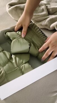 A woman takes ugg boots from a box. warm boots beside a fur coat and winter hats, seasonal wardrobe preparation, winter footwear and clothing for cold weather.