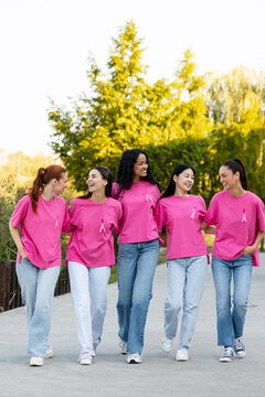 Diverse women supporting breast cancer awareness walking outdoors