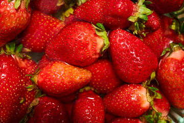 Red strawberries sit in a bowl filled with water. The close-up view shows the texture and shine of the fruit. Light reflects off the surface. This captures the freshness of the strawberries. © bondarillia