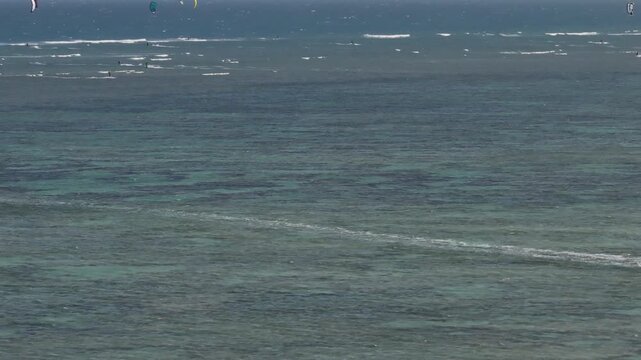 Aerial drone view of kite surfers riding the waves at My Hoa Beach in Vinh Hai, Khanh Hoa, Vietnam, showcasing a spectacular coastal landscape under bright sunlight. 
