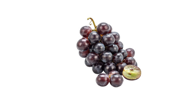 A bunch of dark purple grapes with one grape cut in half, showing the translucent green interior, isolated on a black background, studio shot