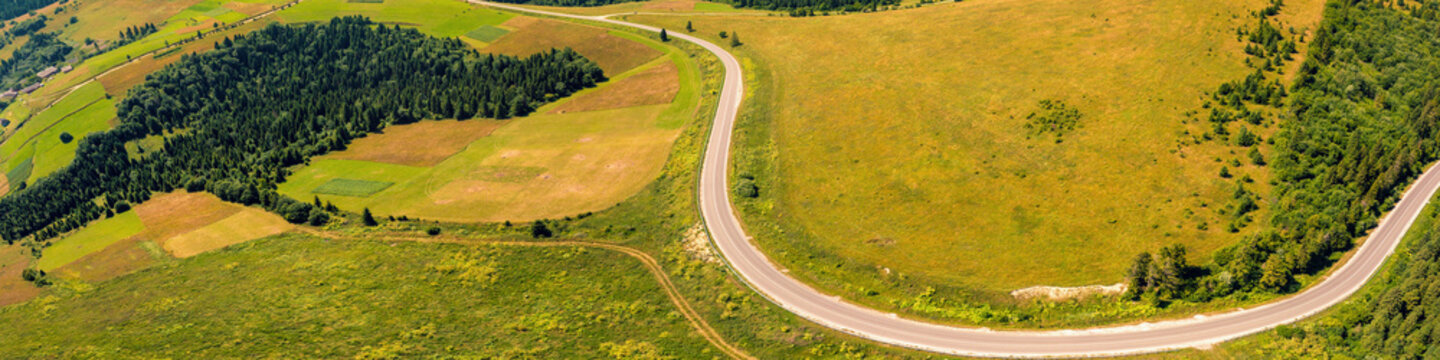 Panoramic aerial view of the countryside, country road, and cultivated and uncultivated fields in the hills