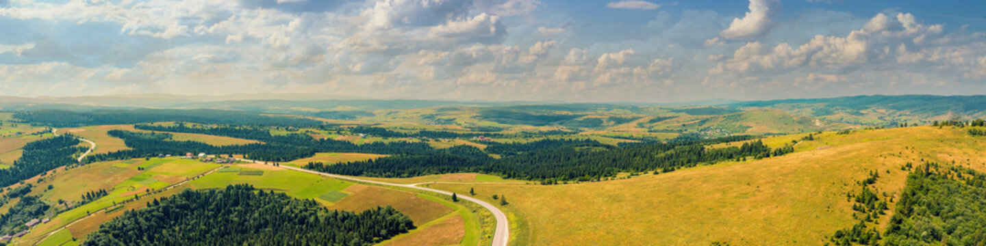 Panoramic aerial view of the countryside, country road, and cultivated and uncultivated fields in the hills