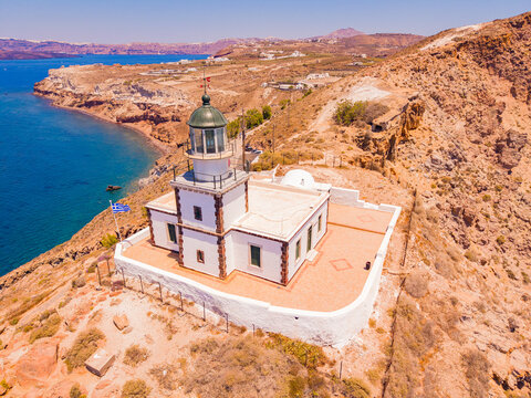 High angle drone aerial view of historic Faros Akrotiri Lighthouse on cliff in Santorini Greece