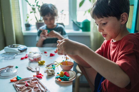 A boy plays with play dough at a table indoors