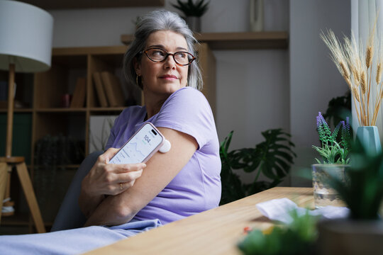 Woman using glucose monitor with mobile device for diabetes management
