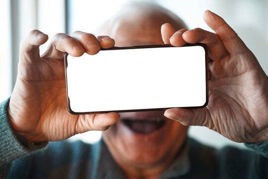 Cheerful senior man holds a smartphone with a blank mockup screen