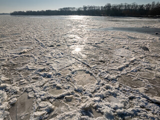 Fototapeta premium Ice floe on frozen Brda River under bridge at sunrise.