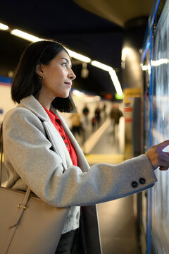 Young woman buying a drink at a metro station vending machine