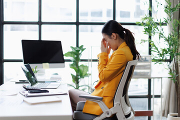 Overworked businesswoman suffering from burnout and headache at office