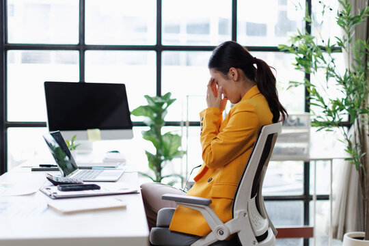 Overworked businesswoman suffering from burnout and headache at office