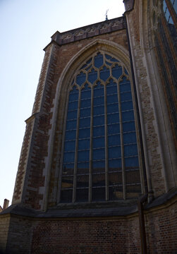 Large gothic arched window with blue glass on a historic old brick church or cathedral building.