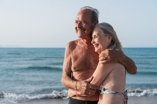Happy couple hugs on the beach by the ocean during summer vacation