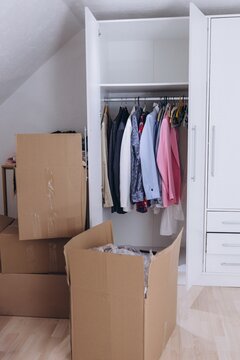 Wardrobe with clothes and unpacked moving boxes in new home
